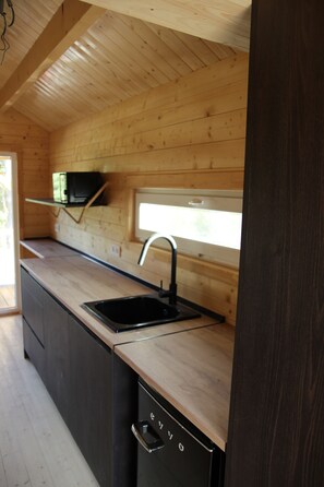 A modern kitchen with wooden cabinetry, a black sink, and a window above the countertop.