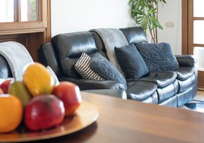 Ein modernes Wohnzimmer mit einem Ledersofa, einem Holztisch und einer Obstschale.
