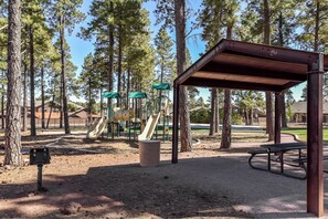 A playground with slides and climbing structures, surrounded by tall trees. - 2 Suite to be good! Escape to the Mountains! (Flagstaff)