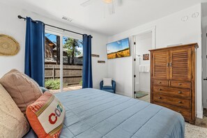 Ein Schlafzimmer mit einem Bett, einem Holzschrank, einem Fernseher und Blick ins Freie.