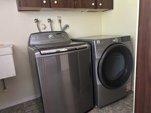 A compact laundry area with a front-loading washer and a stacked dryer. - Waterfront Retreat on Hammersley Inlet (Shelton)