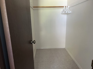 A room with a carpeted floor, a wooden door, and a white wall with a hanging garment rack. - Waterfront Retreat on Hammersley Inlet (Shelton)