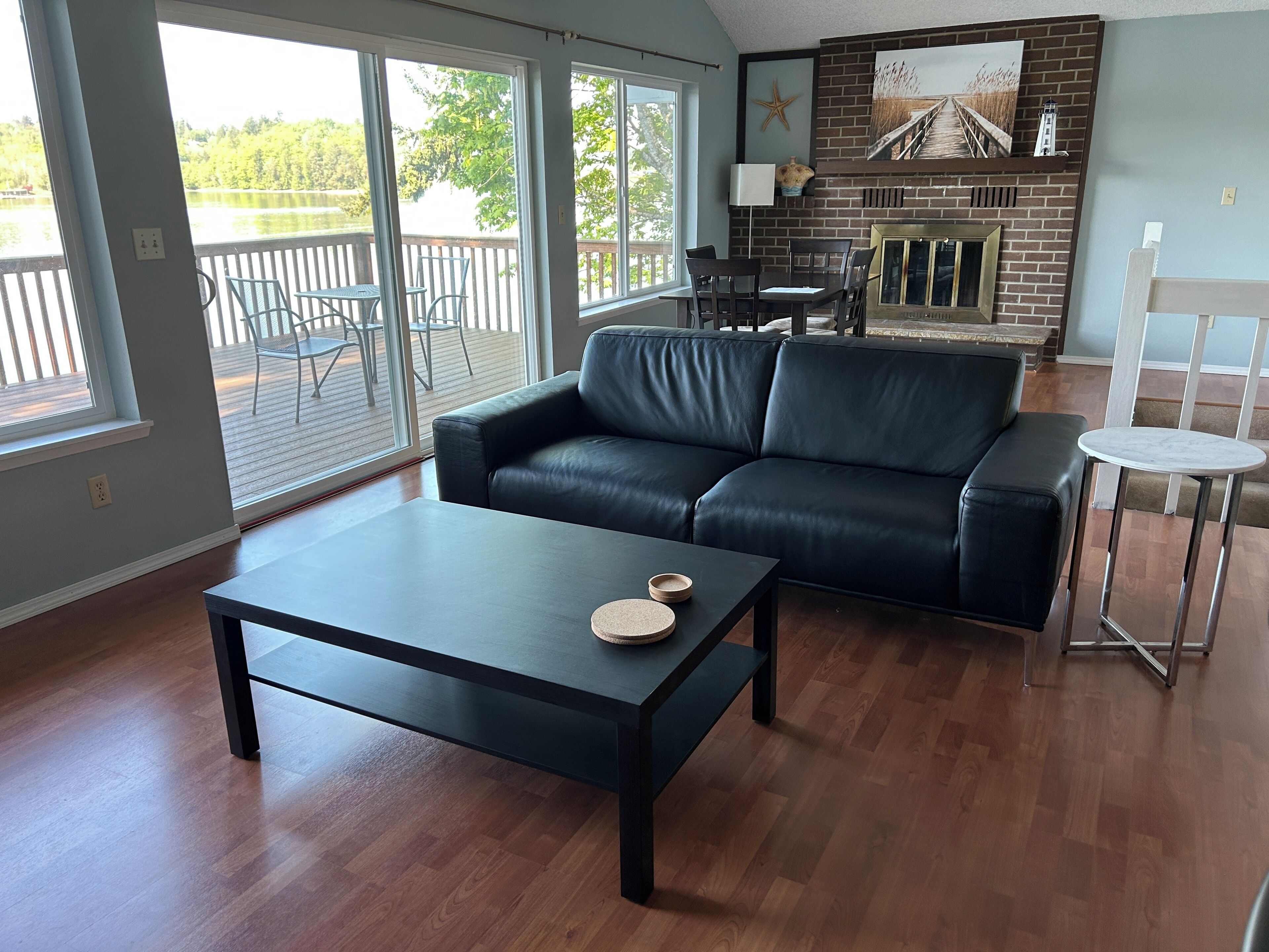 A living room with a black leather sofa, a coffee table, and a fireplace.