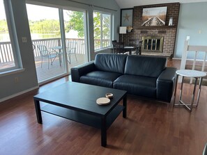 A living room with a black leather sofa, a coffee table, and a fireplace. - Waterfront Retreat on Hammersley Inlet (Shelton)
