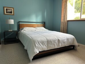 A bedroom with a bed, a nightstand, a lamp, and a window with curtains. - Waterfront Retreat on Hammersley Inlet (Shelton)