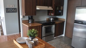 Una cocina moderna con armarios de madera, estufa de acero inoxidable, microondas y refrigerador.
