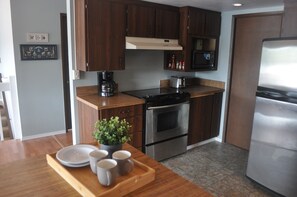 A modern kitchen with wooden cabinets, a stainless steel stove, a microwave, and a refrigerator. - Waterfront Retreat on Hammersley Inlet (Shelton)
