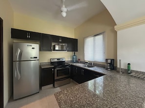 A kitchen with a refrigerator, microwave, stove, oven, and granite countertop.