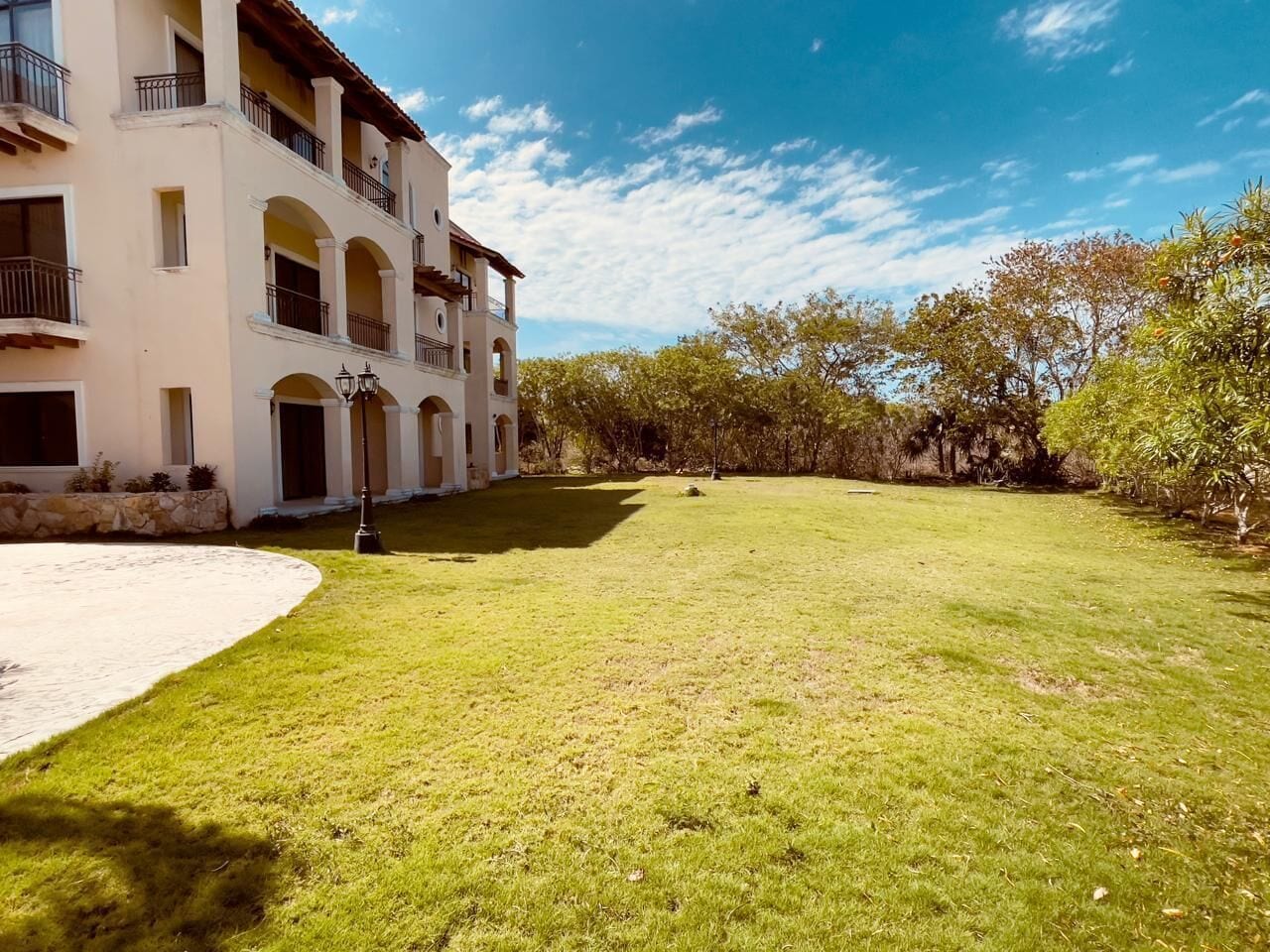 A multi-story building with a courtyard, a paved area, and a lawn.