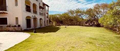 A multi-story building with a courtyard, a paved area, and a lawn.