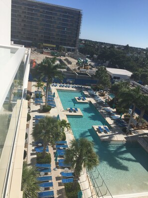 Uma área de piscina de hotel com várias piscinas, espreguiçadeiras e palmeiras.
