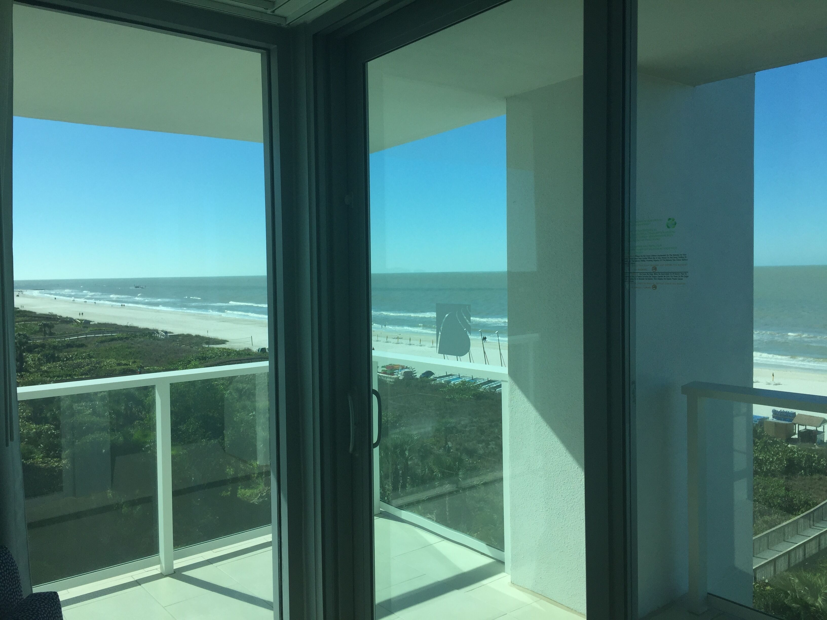 A balcony with a view of the beach and ocean.