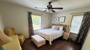 A bedroom with a bed, a nightstand, a chair, a window with curtains, and a ceiling fan. - Pet-Friendly Home Near Dragon Con & Downtown (Atlanta)