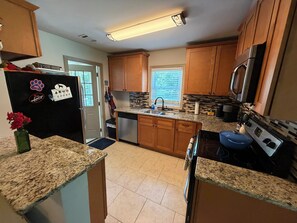 A kitchen with wooden cabinets, granite countertops, a stainless steel refrigerator, a dishwasher, a stove, and a microwave. - Pet-Friendly Home Near Dragon Con & Downtown (Atlanta)