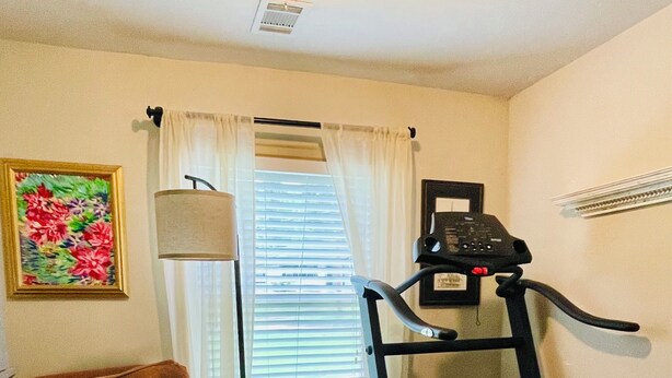 A room with a treadmill, a cushioned chair, a window with blinds, and a wall-mounted air conditioner. - Pet-Friendly Home Near Dragon Con & Downtown (Atlanta)