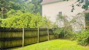 A backyard with a wooden fence, a grassy lawn, and a house in the background. - Pet-Friendly Home Near Dragon Con & Downtown (Atlanta)