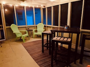 Quarto com uma mesa, duas cadeiras, um tapete pequeno e uma janela com vista para um edifício.