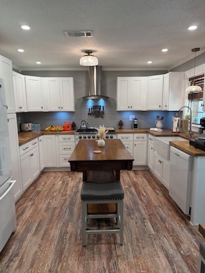 Una cocina moderna con armarios blancos, una mesa de comedor de madera y un banco.