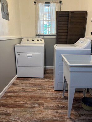 Un cuarto de lavandería con lavadora, secadora y puertas de madera apiladas.