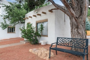 Een bank, een boom en een gebouw met een raam en een deur.