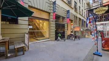 Eine Straße mit einem Gebäude, das eine Treppe zum Eingang, ein Schild für das Restaurant 'The Me' und ein Schild mit der Aufschrift 'Cafe Bar Open' zeigt.
