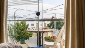 Habitació amb un llit, vistes al carrer i un balcó amb taula i cadires.