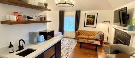 A compact living space with a kitchenette, a sofa, a dining area, and a fireplace.