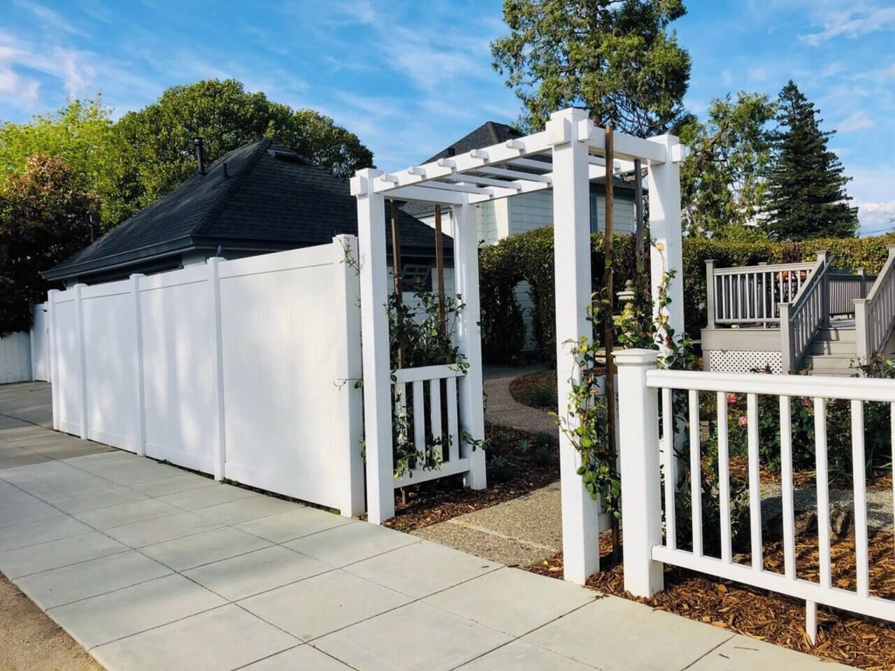 A covered patio area with a white fence and a pergola structure.