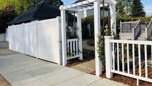 A covered patio area with a white fence and a pergola structure.