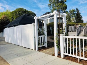 A covered patio area with a white fence and a pergola structure.