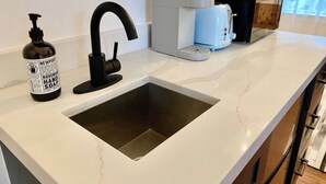 A kitchen with a built-in sink, a coffee maker, and a bottle of hand soap.