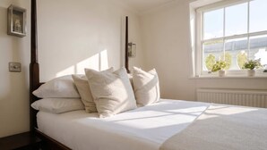 Ein Schlafzimmer mit Himmelbett, einem Fenster mit Pflanzen und einer Heizung.