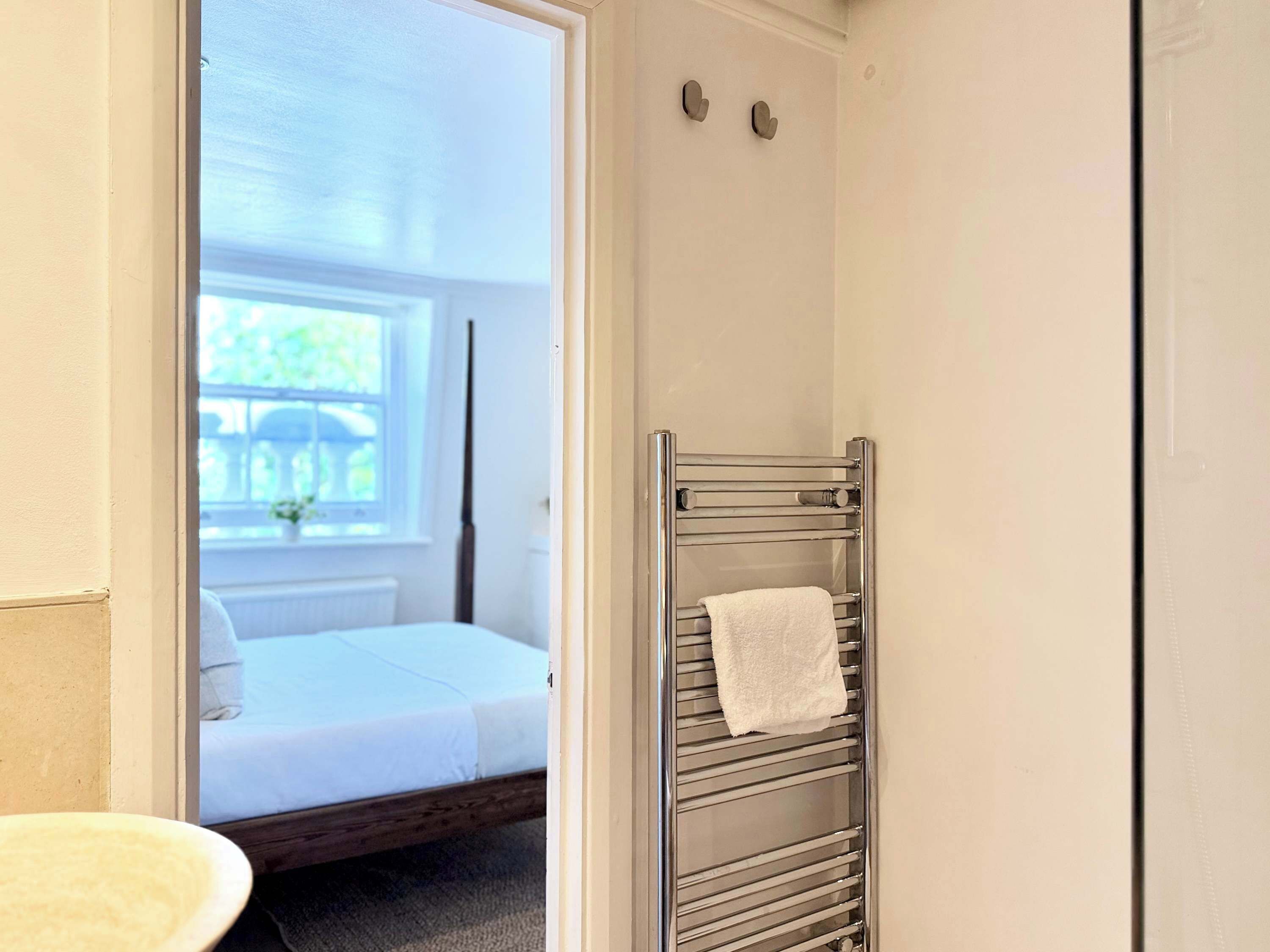 A bathroom with a white bathtub, a white sink, and a towel rack with a white towel.
