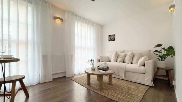 A living room with a sofa, a coffee table, a small side table, and a potted plant. - Chic Marble Arch w/ 100" Cinema & Premium Mattress (London)