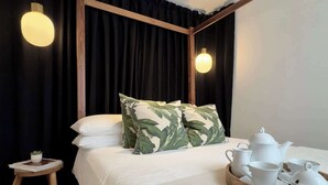 A bedroom with a four-poster bed, a bedside table with a plant, and a tray of white tea set. - Chic Marble Arch w/ 100" Cinema & Premium Mattress (London)