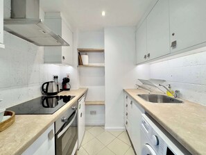 Een moderne keuken met een kookplaat, oven, spoelbak en een ingebouwde vaatwasser.