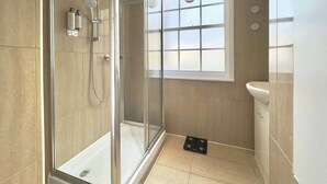 A modern bathroom with a glass-enclosed shower, a window with frosted glass, and a white sink. - Chic Marble Arch w/ 100" Cinema & Premium Mattress (London)