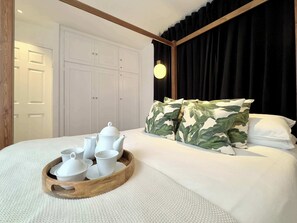 A neatly made bed with a tray of white tea set, a wooden headboard, and camouflage pillows. - Chic Marble Arch w/ 100" Cinema & Premium Mattress (London)