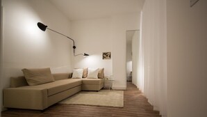 A minimalist living room with a sofa, a rug, a lamp, and a framed picture on the wall. - St. Luke's View, Shoreditch, by the Design Traveller (London)