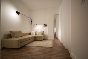 A minimalist living room with a sofa, a rug, a lamp, and a framed picture on the wall. - St. Luke's View, Shoreditch, by the Design Traveller (London)