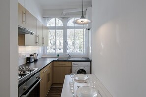 A modern kitchen with a gas stove, dishwasher, and a window providing natural light. - St. Luke's View, Shoreditch, by the Design Traveller (London)
