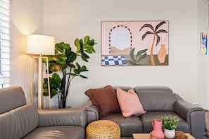 Ein modernes Wohnzimmer mit einem grauen Sofa, einer Stehlampe und einem Wandbild.