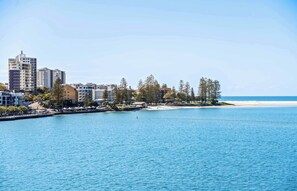 Un paisaje urbano costero con un puerto deportivo, edificios y una playa.