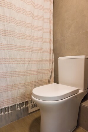 Ein Badezimmer mit Toilette, Duschvorhang und gefliesten Wänden.