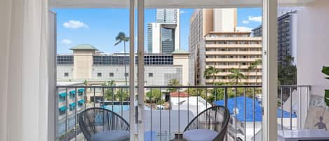 A balcony with two chairs, a table, and a view of urban buildings.