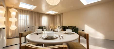 A modern dining room with a round table, chairs, and a chandelier.