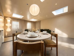 Une salle à manger moderne avec une table ronde, des chaises et un lustre.