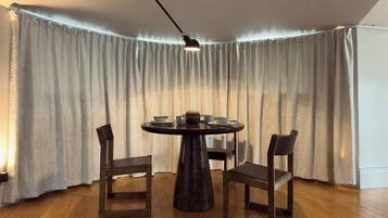 Comedor con una mesa redonda, dos sillas y una lámpara colgante.