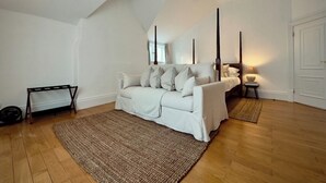 A room with a white sofa, a bed, a standing lamp, and a wooden floor. - Grand 2BR Penthouse | 100" Cinema | Hyde Park (London)