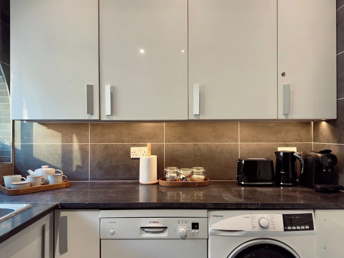 Een moderne keuken met een Bosch vaatwasser, een Kenwood magnetron en een koffiezetapparaat.